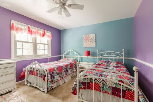 Kids bedroom with purple and teal walls, twin beds, and a dresser