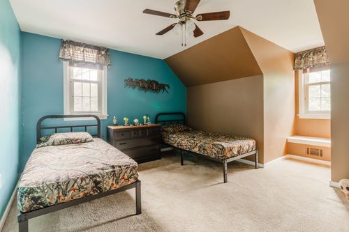 Kids bedroom with teal walls, camo bedding on twin beds, and a dresser