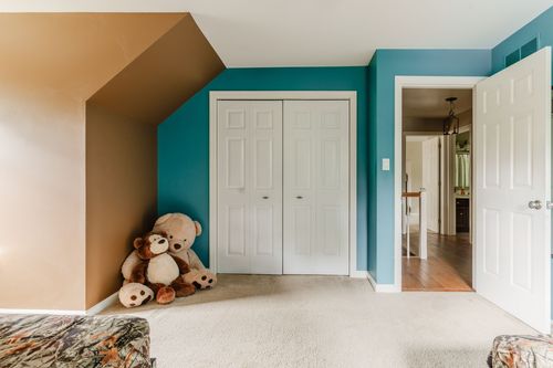 Bedroom nook with teal walls, white closet doors, and stuffed animals on the floor
