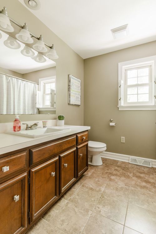 Bathroom with wood vanity, tile floor, and a walk-in shower with curtain