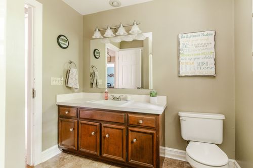 Bathroom with wood vanity, framed mirror, and a nearby toilet