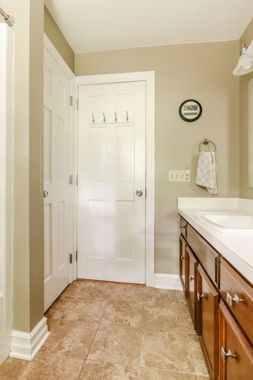 Bathroom hallway with white doors, tile floor, and a wood vanity