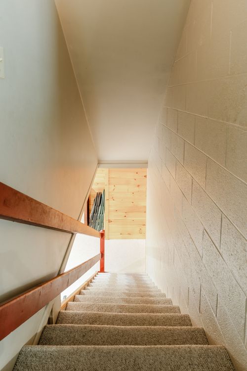 Stairwell leading down to a basement with carpeted steps and cinderblock wall