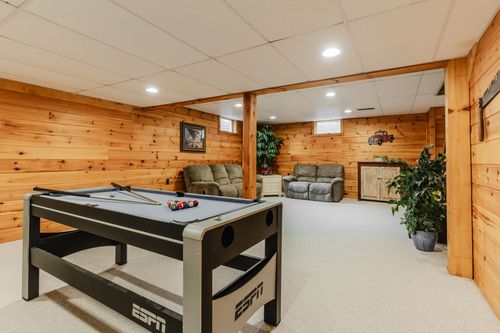 Basement recreation room with a pool table, leather sofas, and pine paneled walls