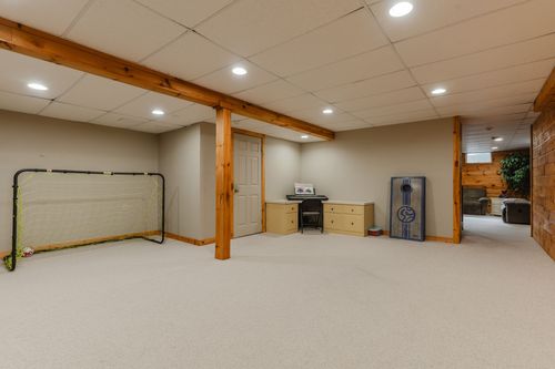 Basement rec room with a soccer goal net, wood beam accent, and a small desk