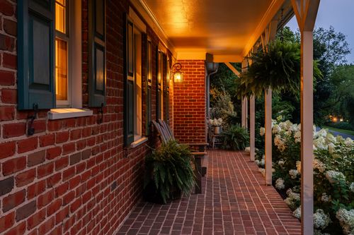 Twilight view of a two-car garage with dark wood siding and pink petunia beds
