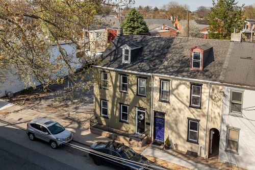 Aerial view of a three-story rowhome with dormer windows on a tree-lined city street