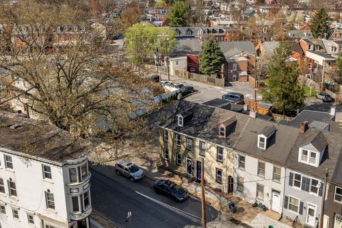 Aerial view of a row of historic townhomes lining a city street among mature trees