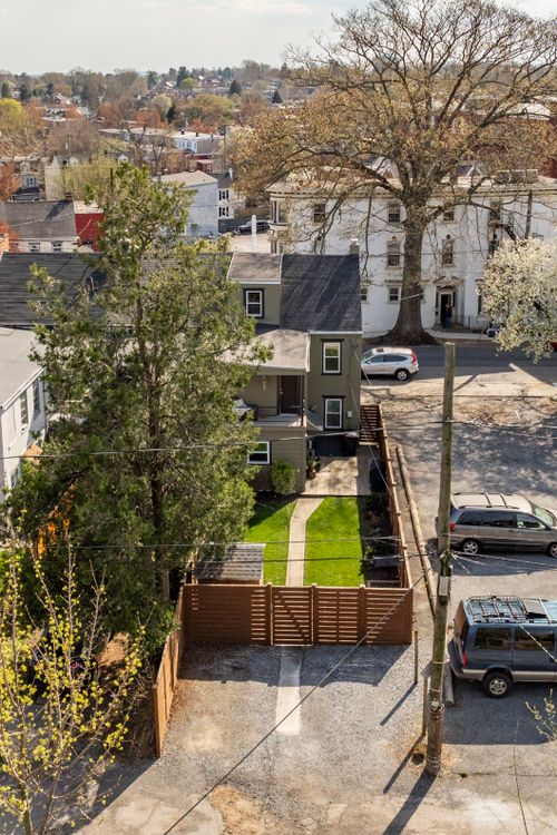 Aerial view of a fenced backyard with a paved patio behind a city rowhome