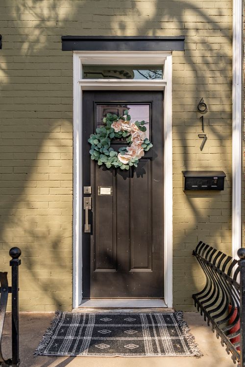 Dark front door with a floral wreath, house numbers, and a wall-mounted mailbox