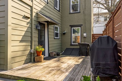 Rear deck with wood boards, a potted plant, and a covered grill against the house
