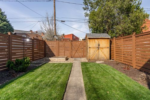 Backyard with a wood storage shed, gated fencing, and a concrete path across the lawn