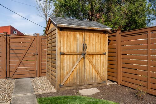 Wood storage shed with double barn doors set against a horizontal wood fence