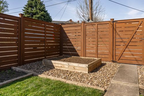 Fenced backyard corner with a raised garden bed and gravel border