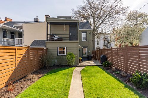 Rear exterior of a home with a covered upper balcony and a fenced backyard path