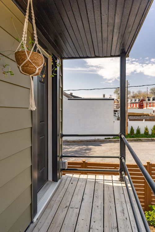 Covered balcony with a hanging macrame planter overlooking a neighboring rooftop