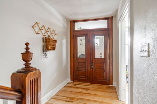 Foyer with wood floors, a double glass-paneled entry door, and a wall-mounted rack