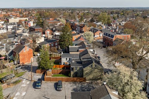 Aerial view of a renovated home with a fenced backyard nestled among city rooftops