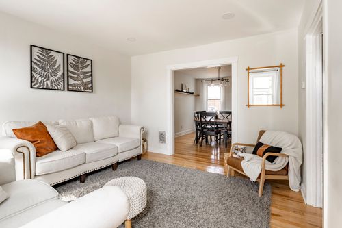 Living room with a cream sofa, fern prints, and a view into the dining room