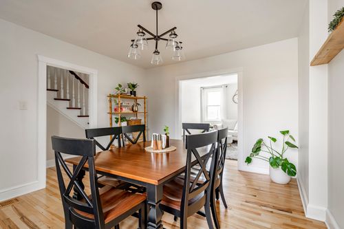 Dining room with a wood table, black X-back chairs, and a view to the staircase