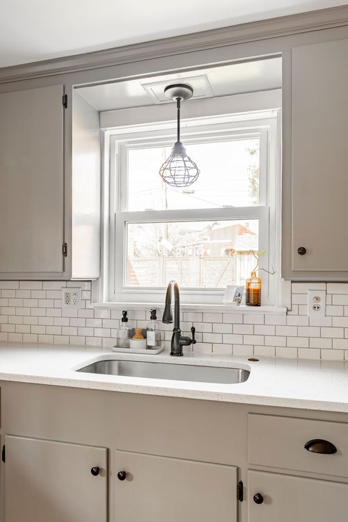 Kitchen sink area with subway tile backsplash, white quartz counter, and pendant light