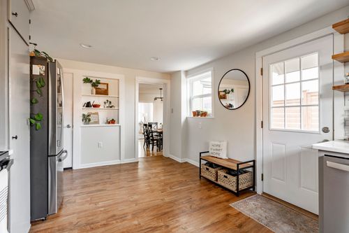 Hallway with wood floors, built-in shelving, a round mirror, and a glass back door