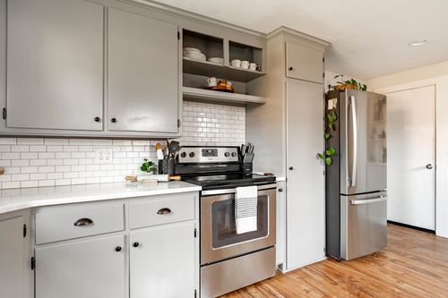 Kitchen with gray cabinets, subway tile, an electric range, and a stainless fridge