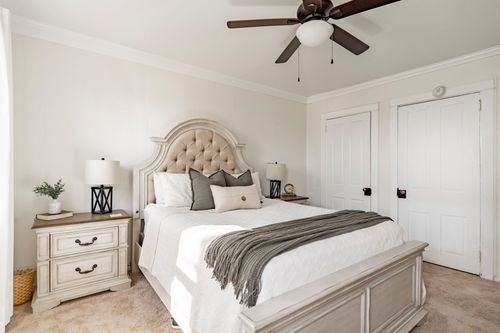 Bedroom with a tufted upholstered headboard, sage throw pillows and paneled closet doors.
