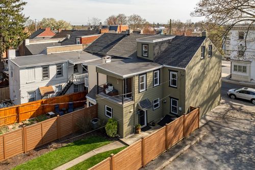 Aerial view of a renovated home with a rooftop deck and dormer windows in a city block