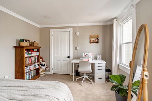 Kids room with a white desk, wicker-basket bookshelf and a plush toy on the floor.