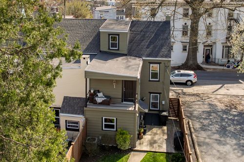 Aerial view of a home with a rooftop deck overlooking a small fenced backyard