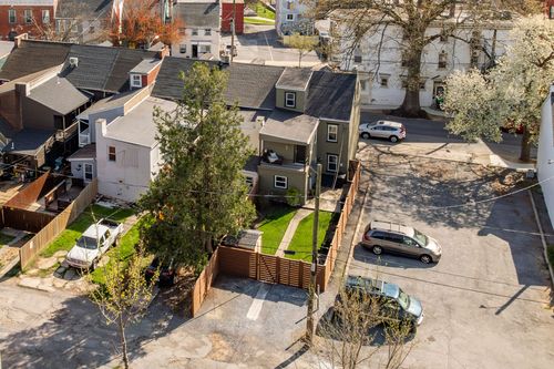 Aerial view of a townhome with a fenced side yard next to a gravel parking area