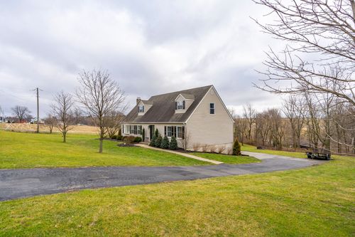 Rear exterior of a cape-style home with a covered deck and exposed lower-level foundation.