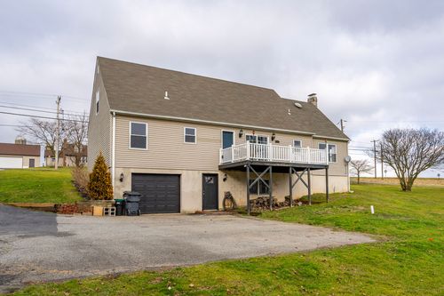Rear exterior with a walkout garage, black door and paved driveway.