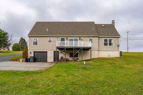 Rear exterior with a raised deck, walkout lower level and an outdoor propane tank.