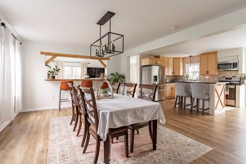 Open dining room with a wood chandelier, farmhouse table and a view into the kitchen beyond.