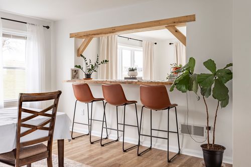 Kitchen pass-through bar with a reclaimed wood beam, live-edge counter and leather barstools.