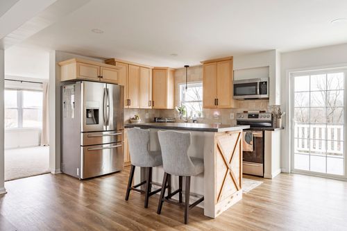 Kitchen island with black barn-door style paneling and gray upholstered stools.