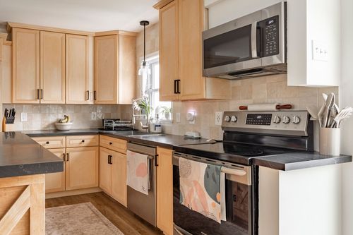 Kitchen close-up with a tile backsplash, stainless range and colorful tea towels.