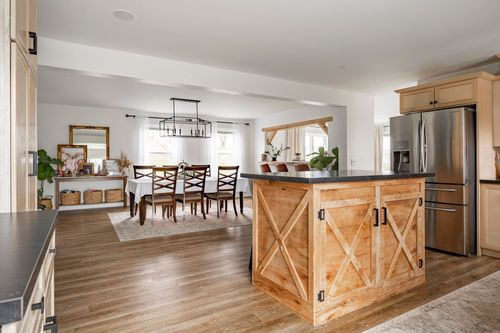 Kitchen with a wood barn-door island, tile backsplash and a dining area beyond.