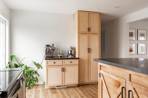 Kitchen coffee station with a built-in pantry cabinet and dark countertop.