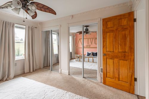 Bedroom with mirrored closet doors, a wood paneled door and a rustic ceiling fan.