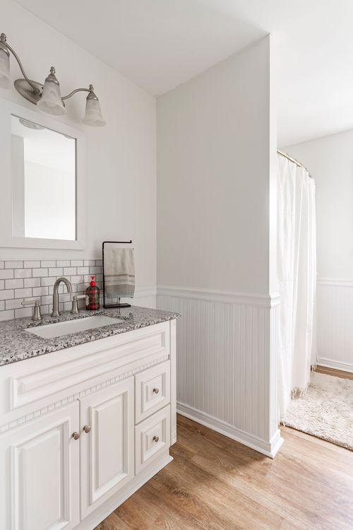 Bathroom with a granite-top vanity, subway tile backsplash and a curtained shower.