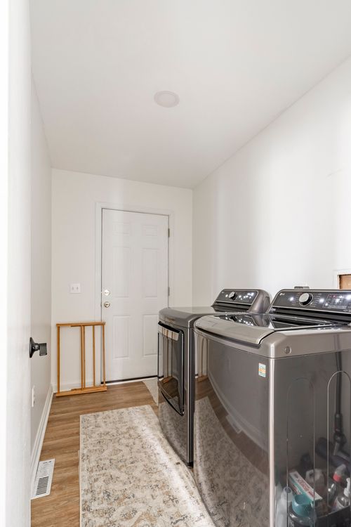 Laundry room with a stacked front-load washer and dryer beside an exterior door.