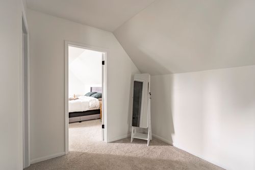 Upstairs hallway opening into a bedroom, with a standing mirror in the corner.