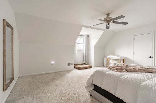 Bedroom with vaulted ceilings, a mirrored dresser and neatly made bed.