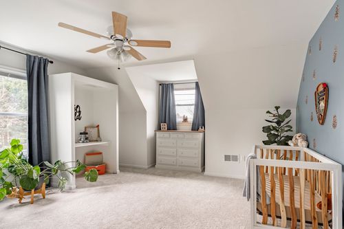 Nursery corner with a navy accent wall, wood dresser and window seat storage.