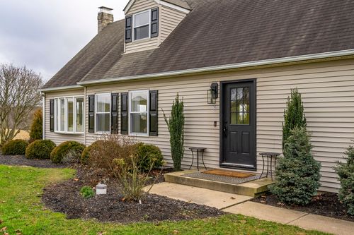 Front entry with a black paneled door, sidelight window, wall lantern and flanking evergreens.