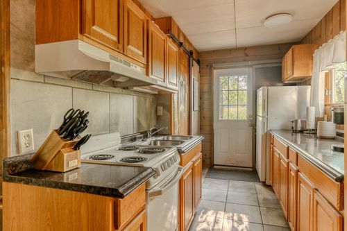 Kitchen with a white range, wood cabinets and a sliding barn door leading to a back entry.