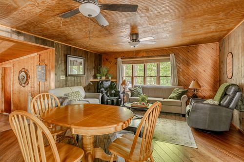 Wood-paneled living area with a round dining table, leather recliner and matching sofas.